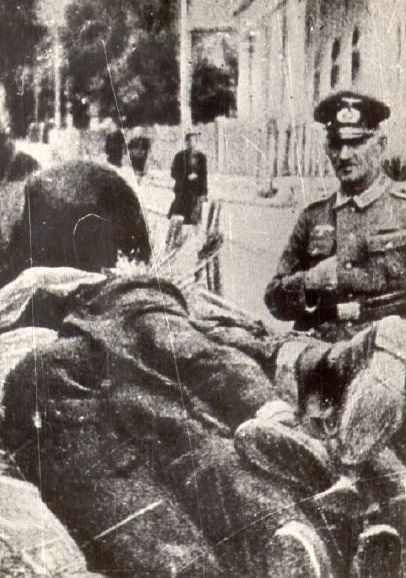 SS officer views a wagonload of corpses